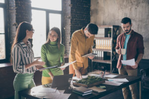 Personas trabajando en una oficina moderna y luminosa con luz natural, vegetación y diseño sostenible.
