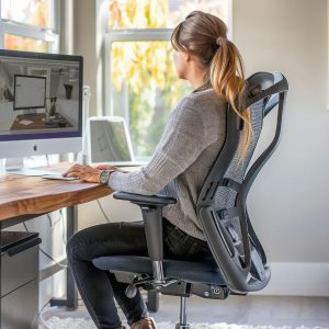 persona trabajando con silla ergonómica y postura correcta en oficina
